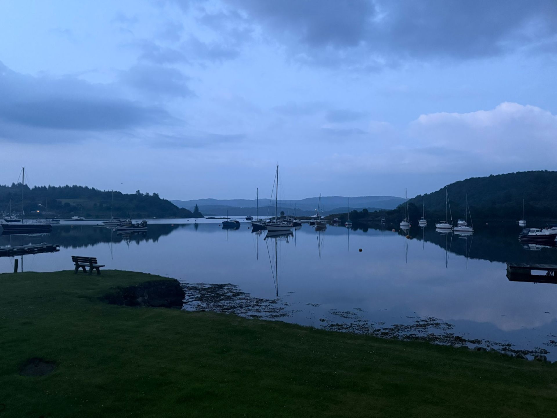 Tayvallich harbour at dusk with moored yachts reflected in still water
